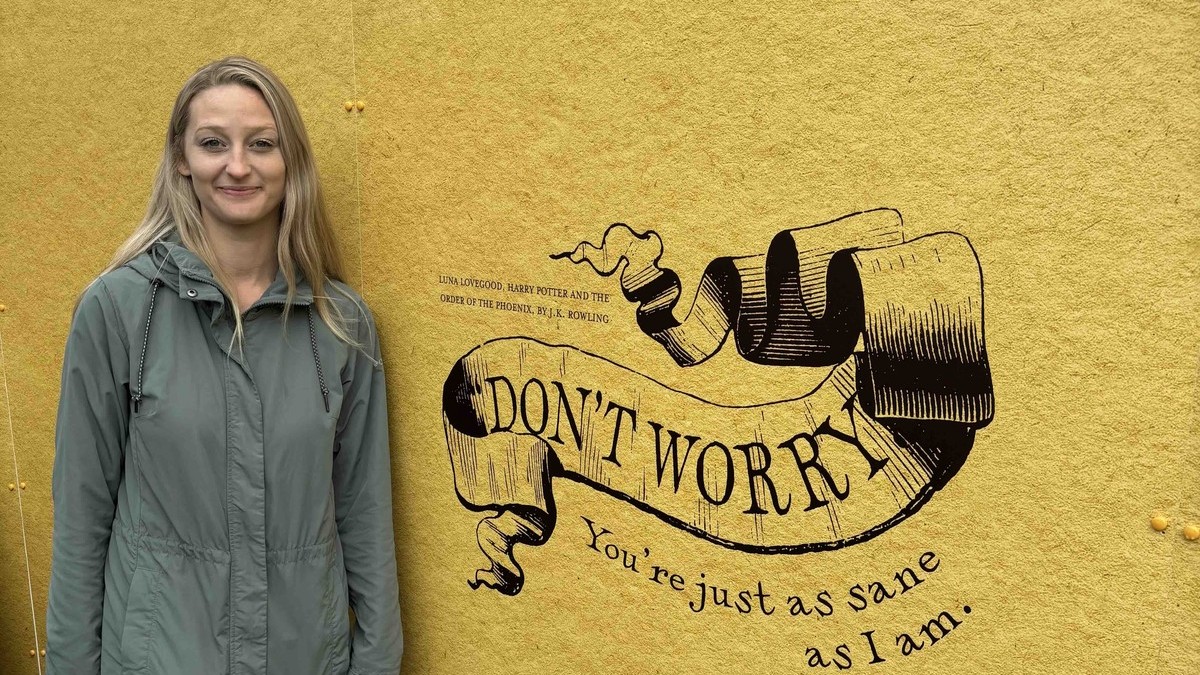 Nicole Skeele, LCSW, ADHD-CCSP, standing next to a Portland mural that reads "Don't worry — you're just as sane as I am."