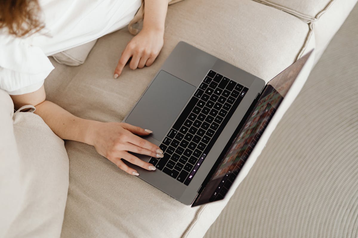 Hands on a laptop during a telehealth therapy session from a comfortable couch